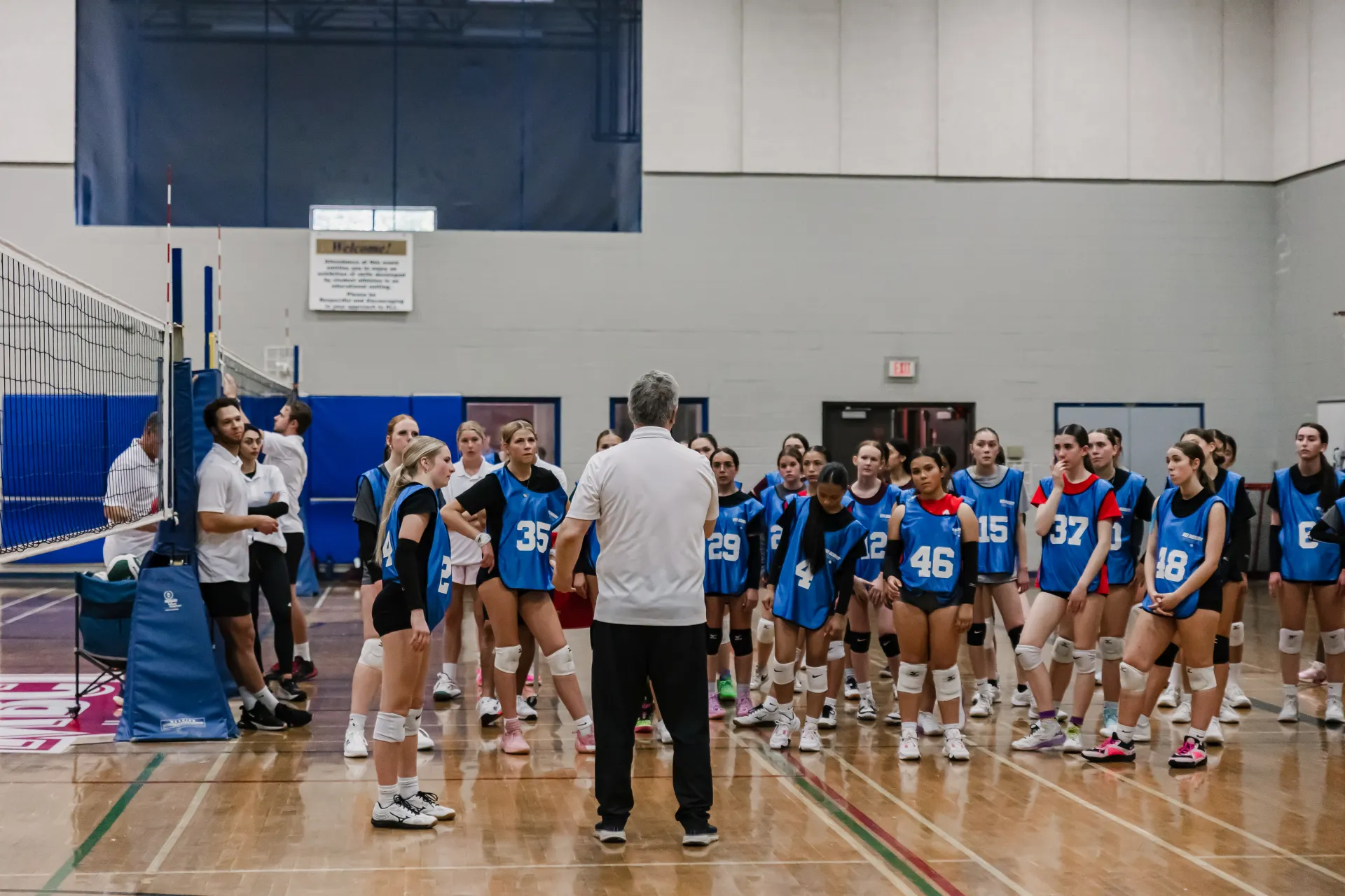 Coach mentoring a young volleyball athlete during a training session