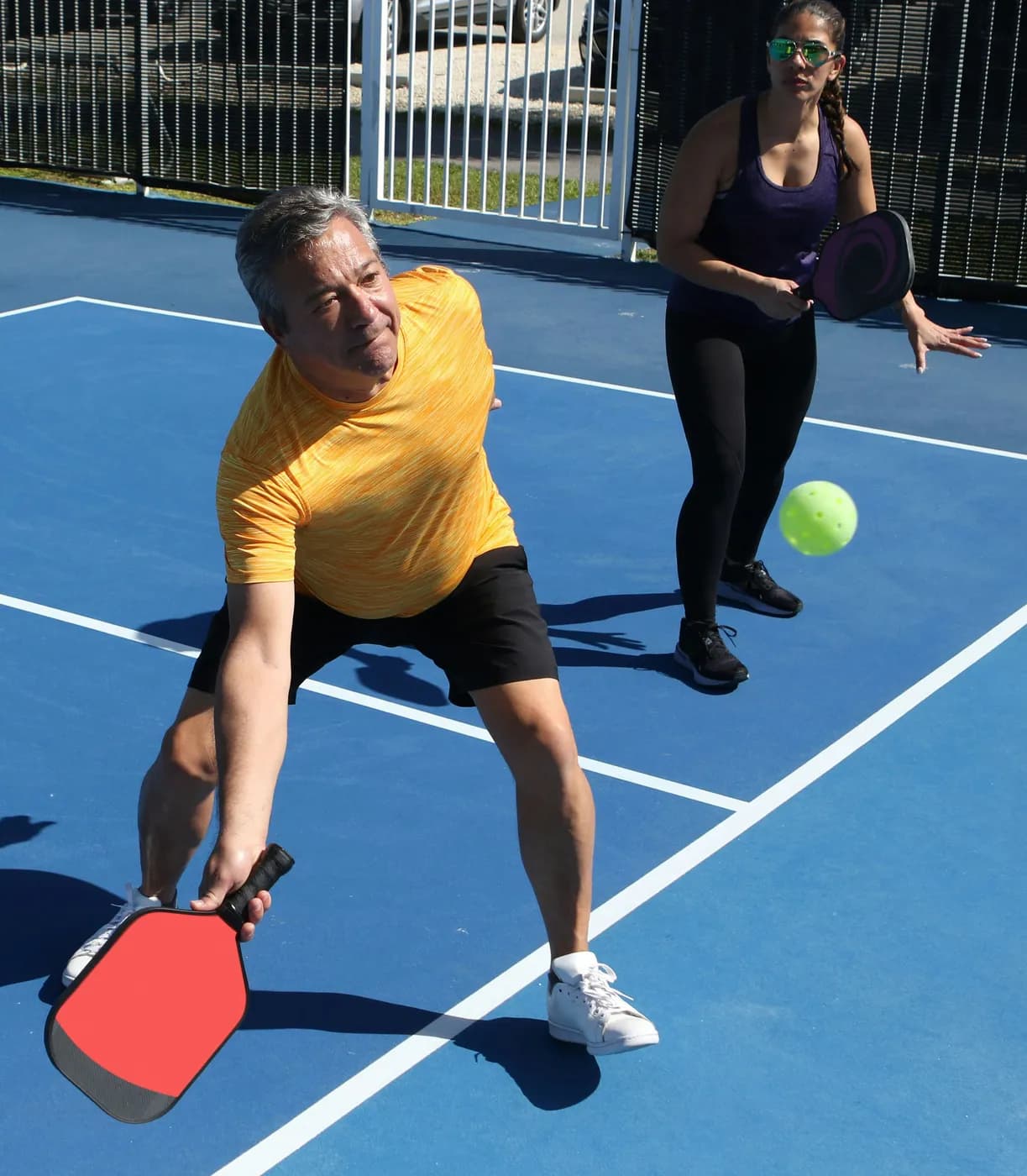 Players with paddles and ball on an indoor pickleball court